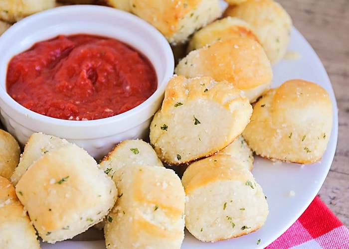 These Garlic Parmesan Pretzel Bites on a white serving plate with a dipping sauce in the middle is an easy super bowl snack