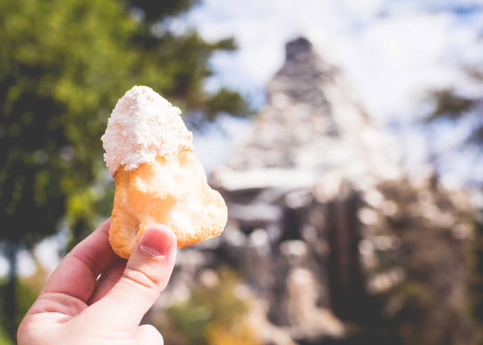 a Disney treat being help up in front of the Matterhorn at Disneyland