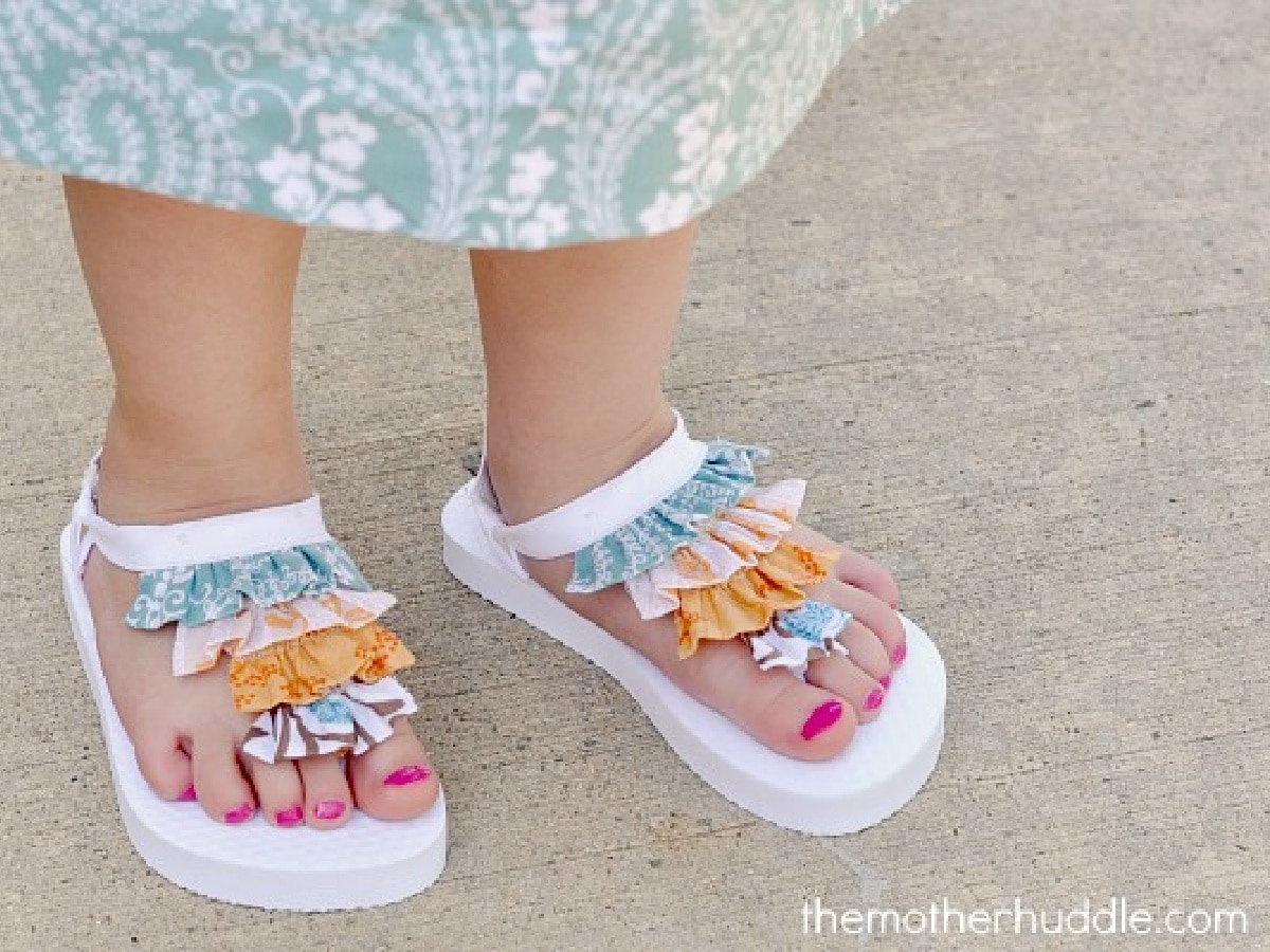 little feet wearing white flip flops with colorful ruffles