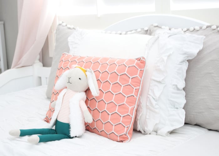 a stuffed rabbit in front of pillows sitting on a bed