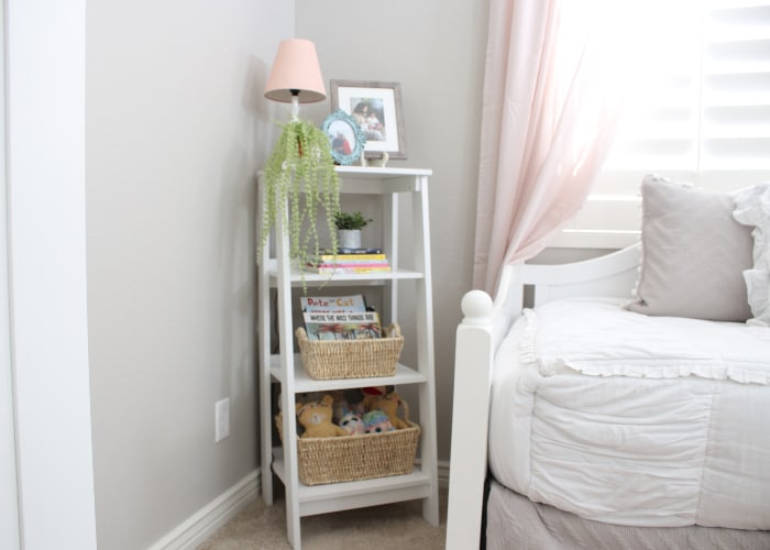 a shelf in a younger girl's bedroom with pictures and baskets on the shelves