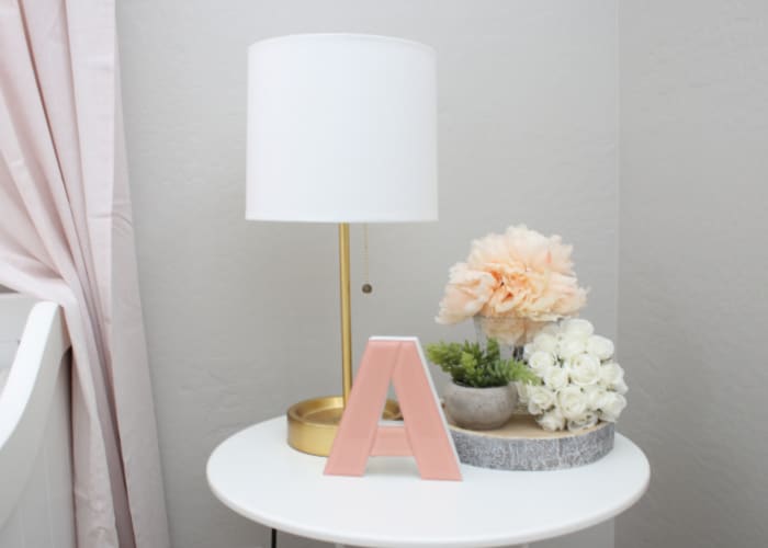 a white circular table with a lamp and a pink letter A on top