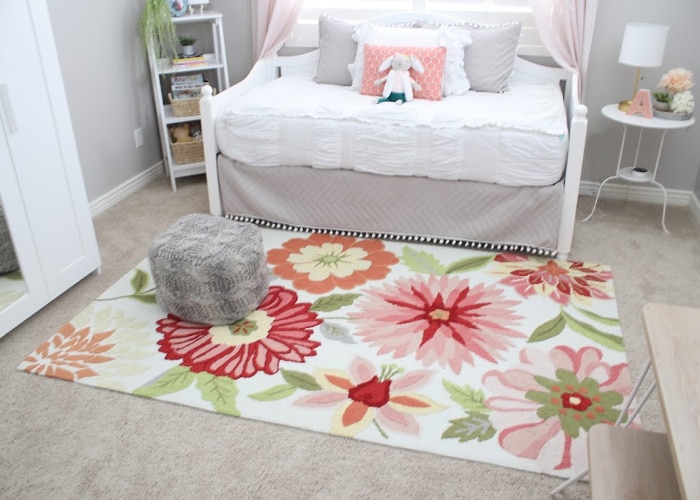 a floral rug on the floor in front of a bed in a room decorated for a girl