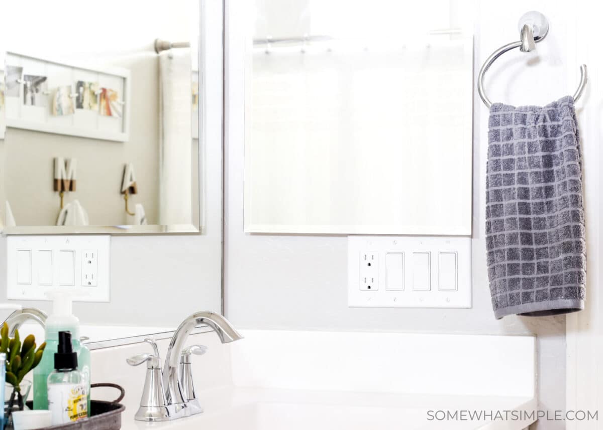 a gray hand towel hanging from a towel rack next to a mirror in bathroom