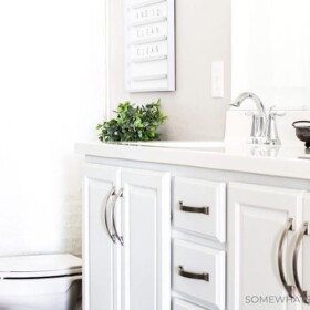 a kids bathroom that has white cabinets with nickle hardware