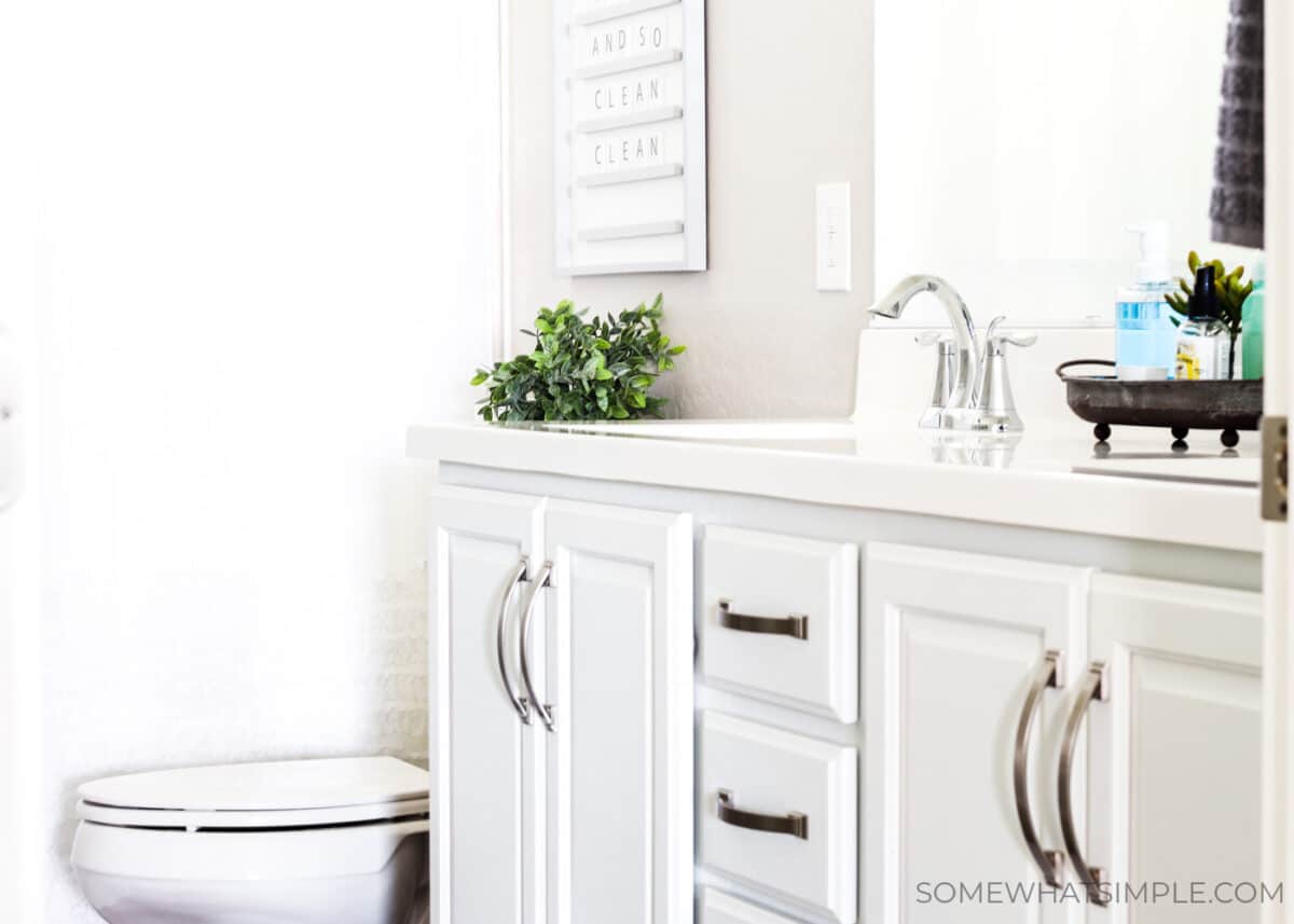 a kids bathroom that has white cabinets with nickle hardware