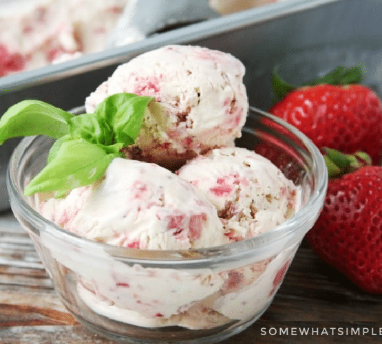 bowl of homemade strawberry ice cream net to strawberries