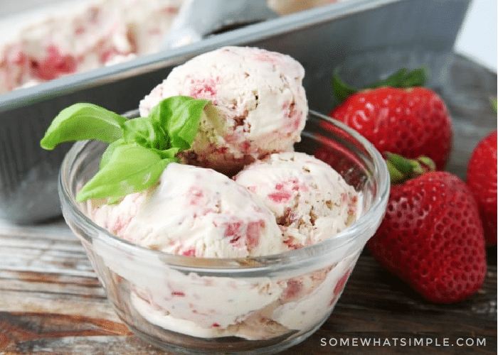bowl of homemade strawberry ice cream net to strawberries