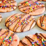 banana cookies topped with drizzled chocolate and colorful sprinkles