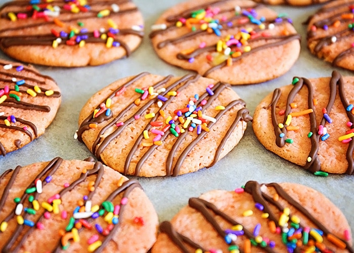 banana cookies topped with drizzled chocolate and colorful sprinkles