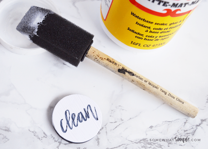 a foam brush has just painted mod podge over a circular magnet with the clean dishwasher free printable