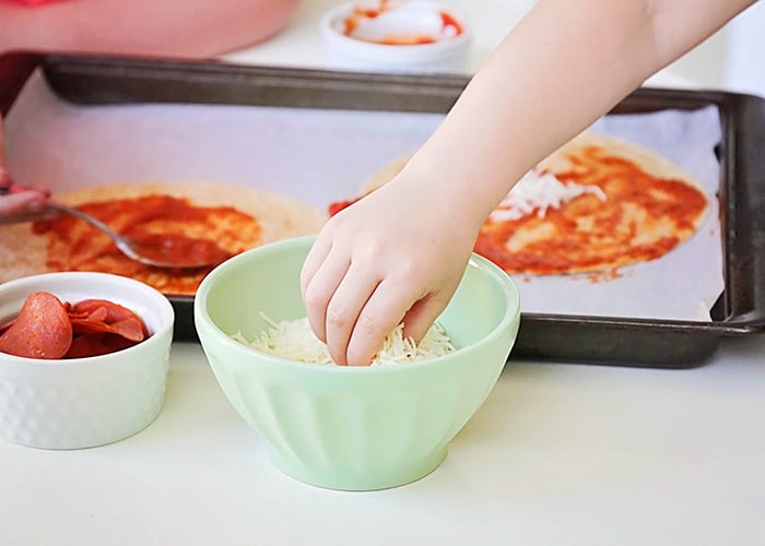 a hand in a bowl of shredded cheese