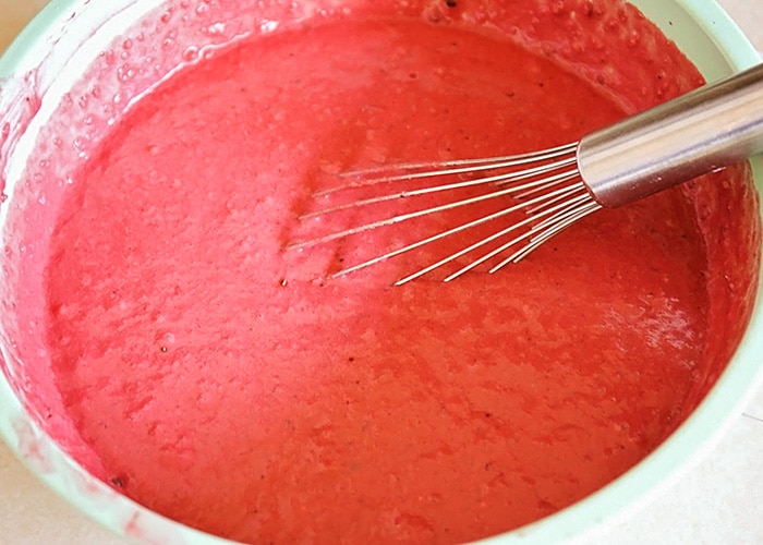 a white bowl full of Red Velvet Pancakes mix with a whisk