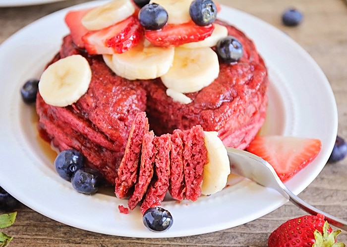 a plate full of Red Velvet Pancakes made with this easy Recipe and topped with bananas strawberries and blueberries