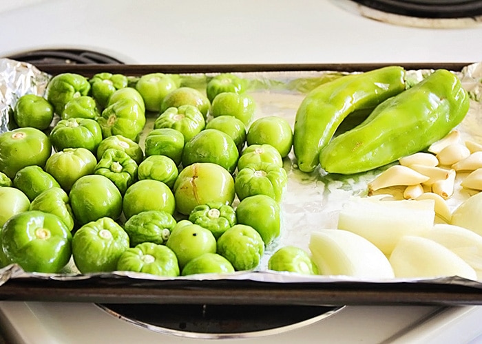 tomatillos garlic and onions on a baking sheet