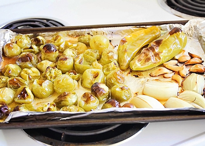 roasted tomatillos, garlic and onions on a baking sheet