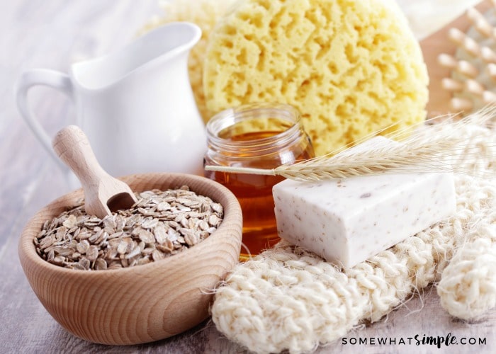 a bowl of oatmeal with a wooden scoop, a jar of honey and a pitcher of milk are essential ingredients for this Oatmeal Face Mask Recipe