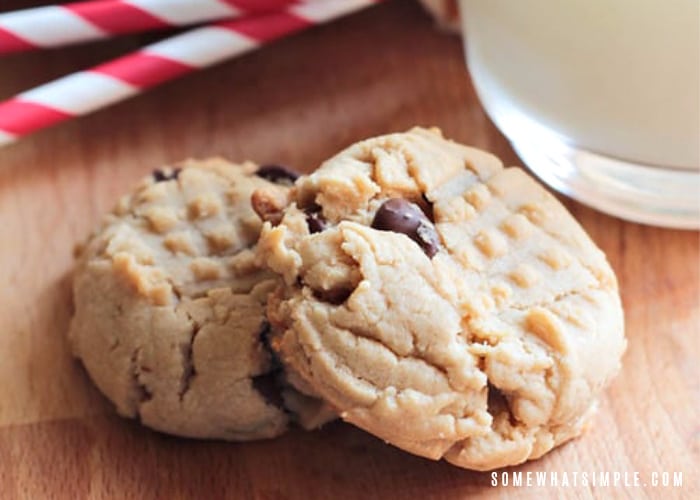 two peanut butter chocolate chip cookies laying on top of each other on a wooden table