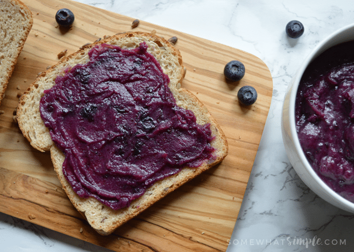 a slice of bread covered in a blueberry honey butter laying on a cutting board