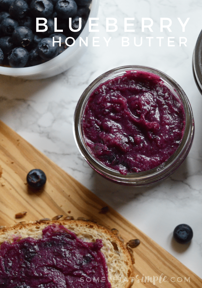 looking down on an open jar of blueberry honey butter and a slice of bread covered in blueberry butter