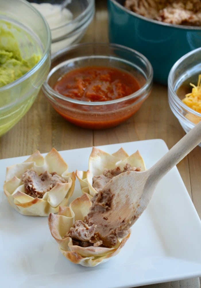 wonton cups being filled with refried beans