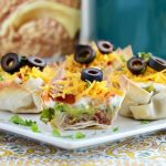 seven layer dip cups on a plate