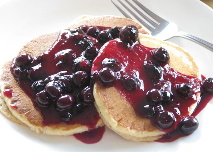 pancakes topped with fresh blueberries and a blueberry syrup