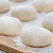 homemade pizza dough on a wood cutting board