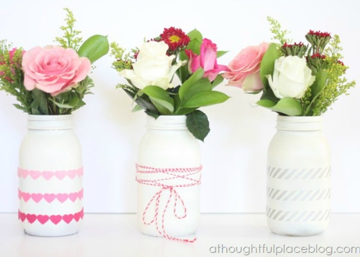 jars painted white with flowers inside that are being used as a vase