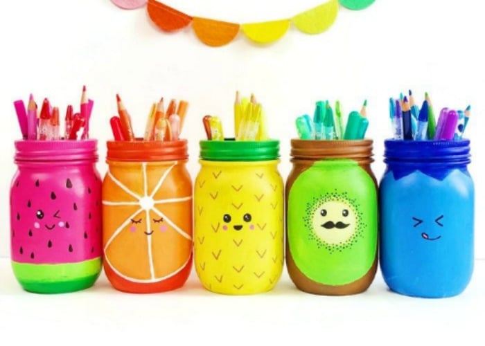 mason jars that are painted to look like different colored fruit. Inside each of them are colored pencils and pens that match the color of the jar