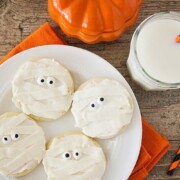 Halloween Mummy sugar Cookies on a plate next to a glass of milk