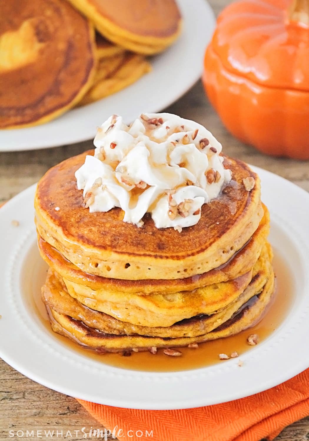 Recipe for Easy Pumpkin Pancakes on a white plate topped with whipped cream