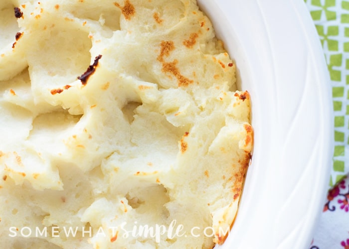 looking down on a bowl of homemade garlic mashed potatoes with Parmesan cheese. The picture is a close up of the bowl, so you can only see about half of the bowl.