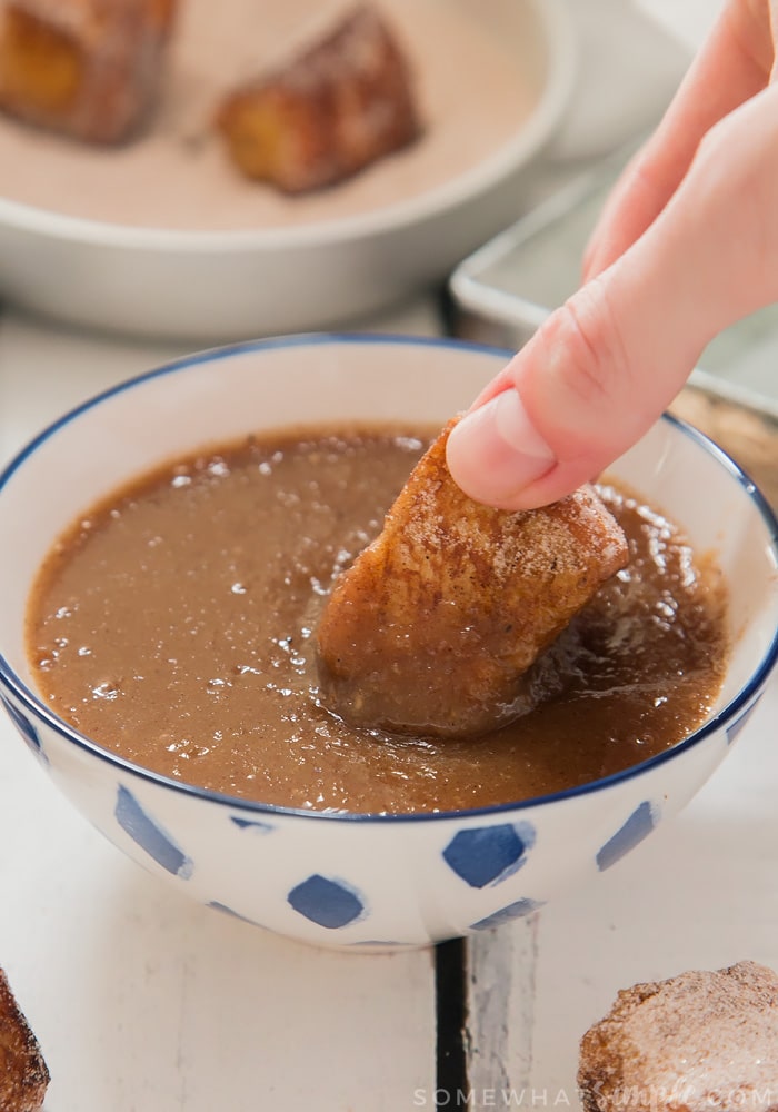 a french toast bite being dipped in a sauce