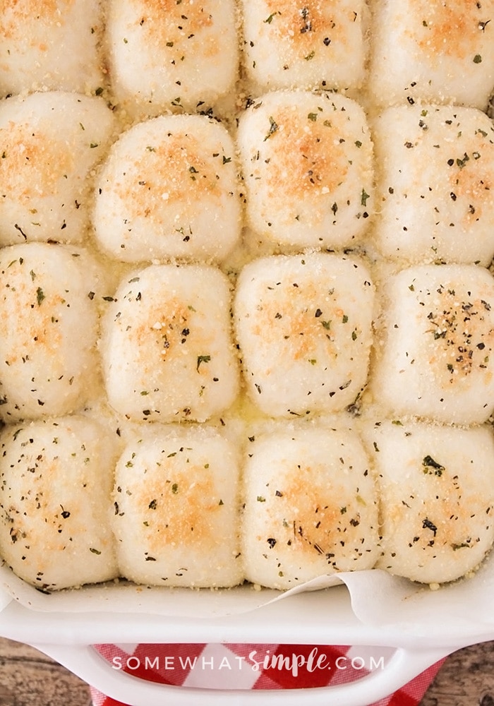 a pan of dinner rolls topped with garlic and parmesan cheese