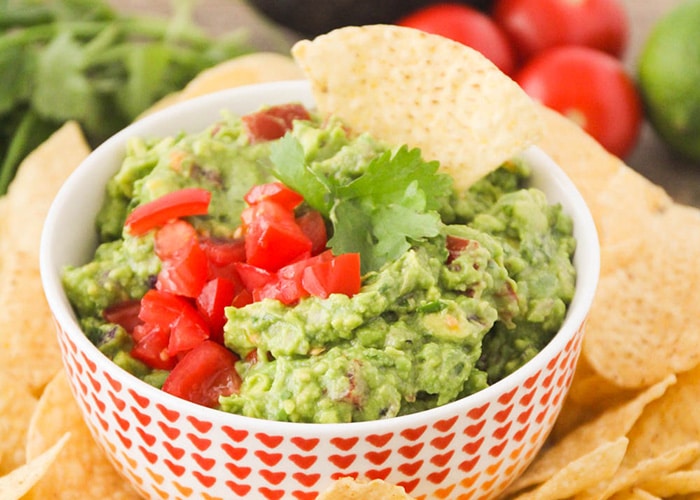 a bowl of Zesty Guacamole next to a pile of tortilla chips