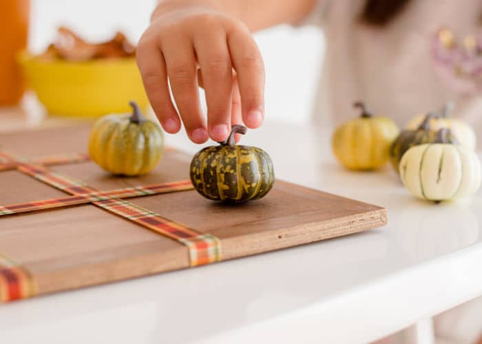 Child playing Tic Tac Toe with Pumpkins