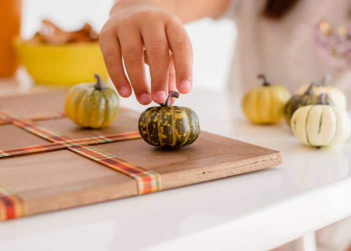 Thanksgiving Activities - A Child playing Tic Tac Toe with Pumpkins