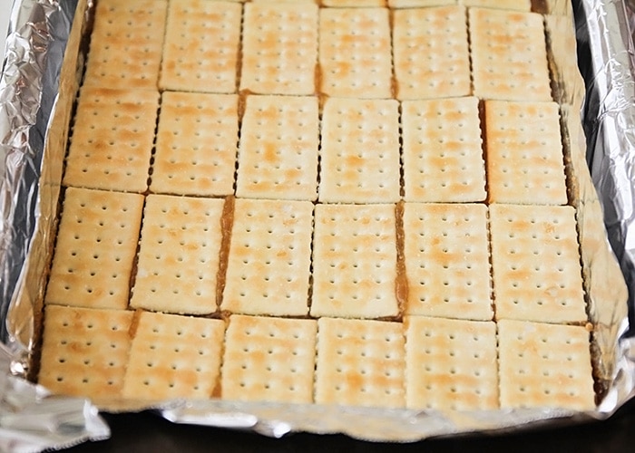 in progress layers of christmas crack toffee made with club crackers