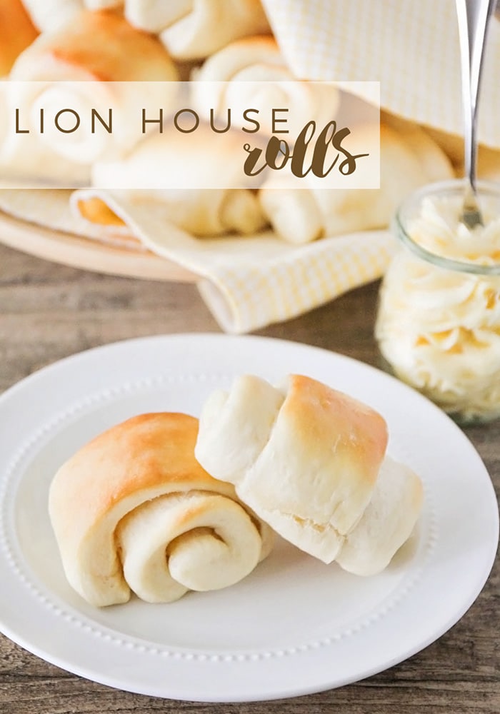 two lion house rolls on a white plate with a side of butter.