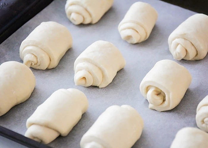 a baking sheet filled with uncooked dinner rolls