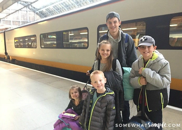 five children standing on the Eurostar train platform in London, waiting to board their train. Behind them is a high speed train that is headed to Paris.