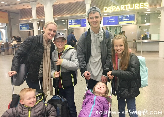 an attractive woman with her 5 kids standing outside of the departure gate at a train station in London