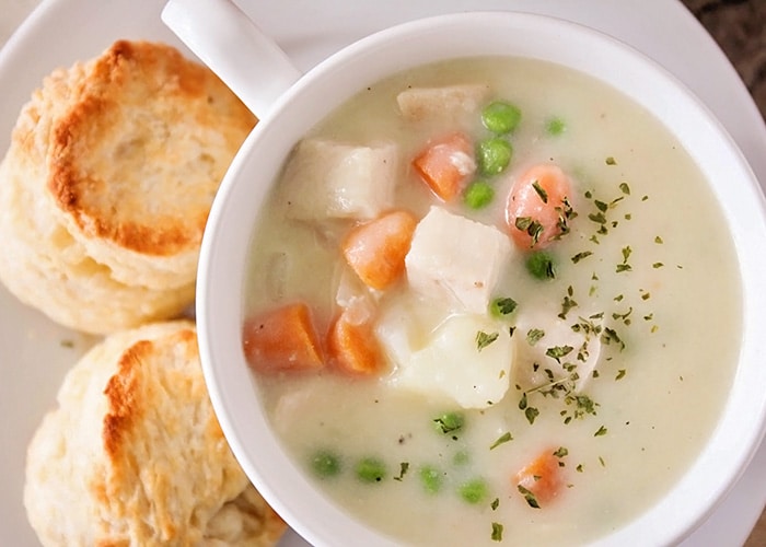 looking down on a bowl of chicken pot pie soup and biscuits