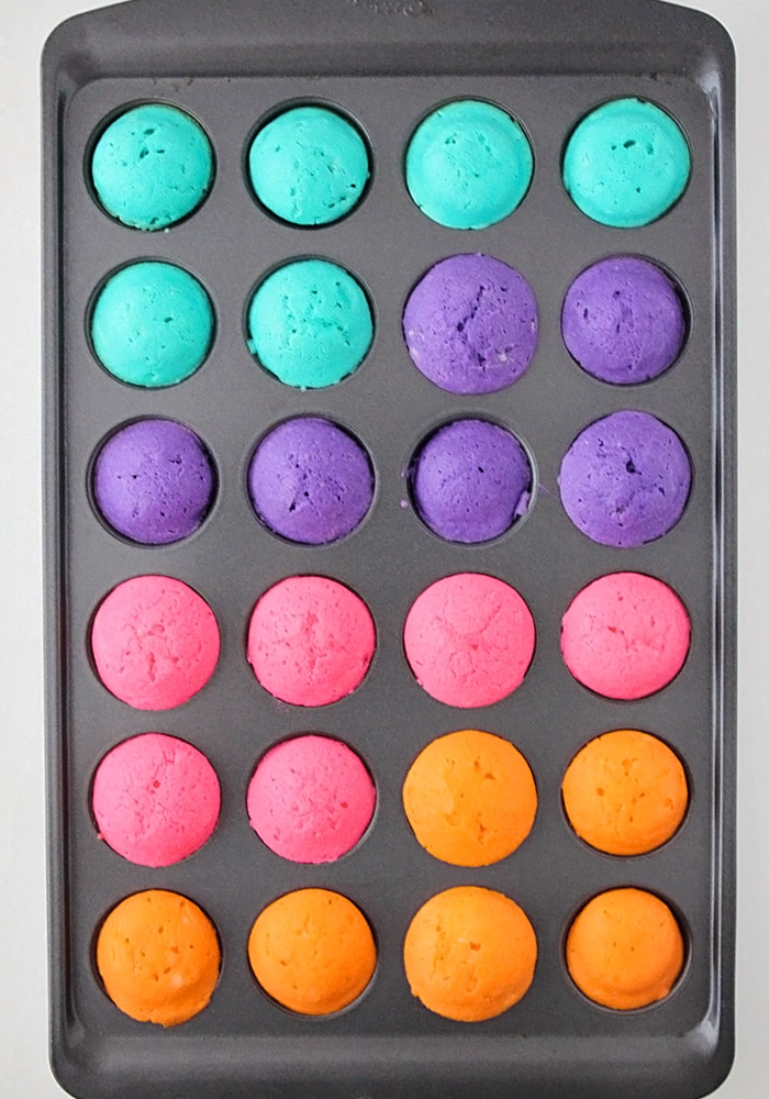 a tin full of different colored mini cupcakes