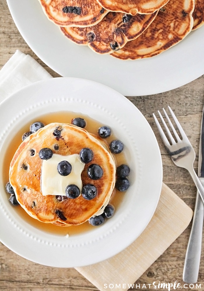 looking down on a pancake topped with butter, syrup and blueberries