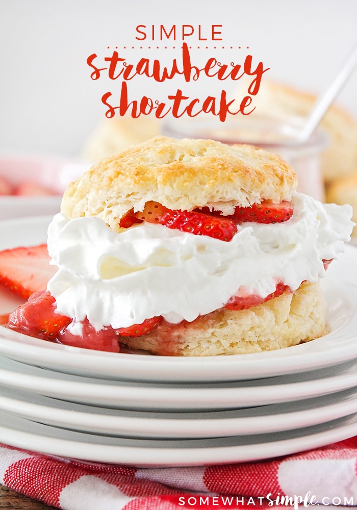 a close up of a piece of strawberry shortcake made with a biscuit filled with whipped cream and sliced strawberries on a stack of white plates. At the top of the image, written in red letters, are the words Simple Strawberry Shortcake