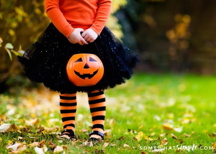 a little girl holding a pumpkin ready to go trick or treating