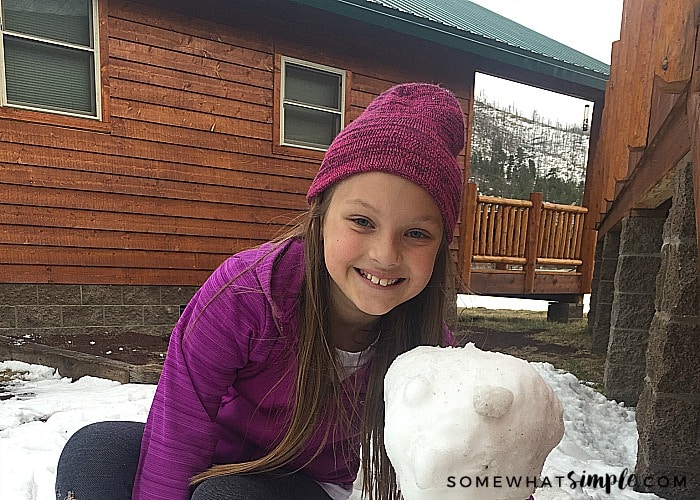 a cute girl next to a small snowman