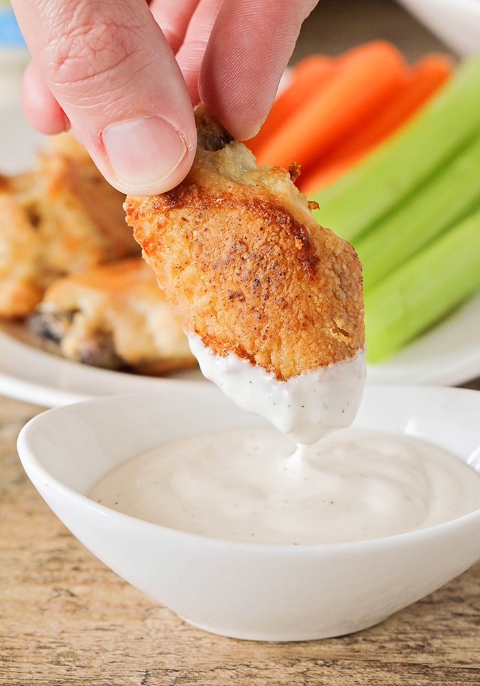 a Crispy Baked Chicken Wing being dipped in ranch